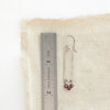A garnet wrapped long forged hoop earring styled next to a ruler for size reference