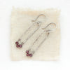 The garnet wrapped forged long hoop earrings styled on tan linen