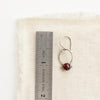 A garnet la cloche earring next to a ruler for size reference