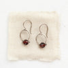 The garnet la cloche earrings styled on tan linen