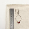 A garnet wrapped teardrop hoop styled next to a ruler for size reference