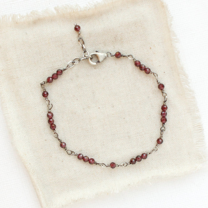 The wrapped garnet bracelet styled on tan linen