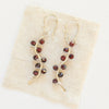 The garnet wrapped silver vine earrings styled on tan linen