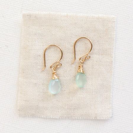 The gold chalcedony drop earrings styled on tan linen