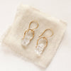 The gold herkimer diamond la cloche earrings styled on tan linen