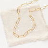 The gold paperclip necklace styled on tan linen