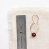 A garnet delhi earring next to a ruler for size reference