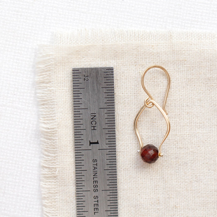 A garnet delhi earring next to a ruler for size reference
