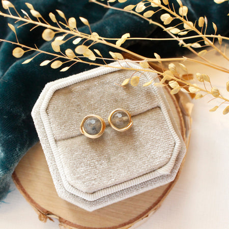 The labradorite wrapped post earrings styled on wood with blue velvet and dried grass