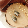 The gold wrapped pyrite earrings styled on wood with orange velvet and dried grass