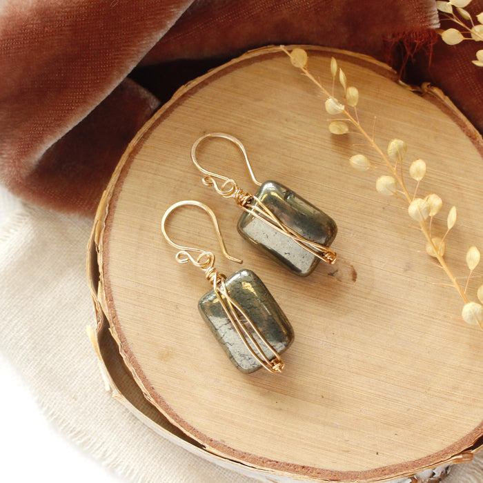 The gold wrapped pyrite earrings styled on wood with orange velvet and dried grass