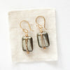 The gold wrapped pyrite earrings styled on tan linen