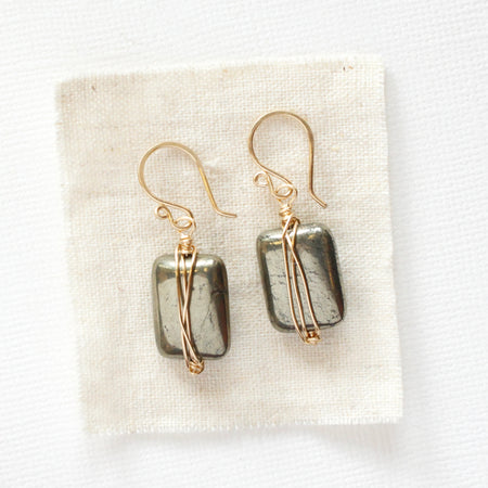 The gold wrapped pyrite earrings styled on tan linen