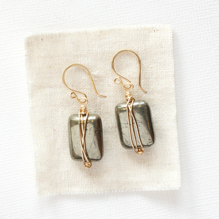 The gold wrapped pyrite earrings styled on tan linen