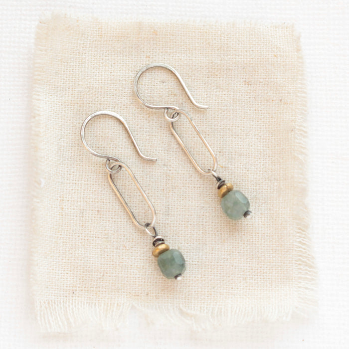 The green apatite hoop earrings styled on tan linen