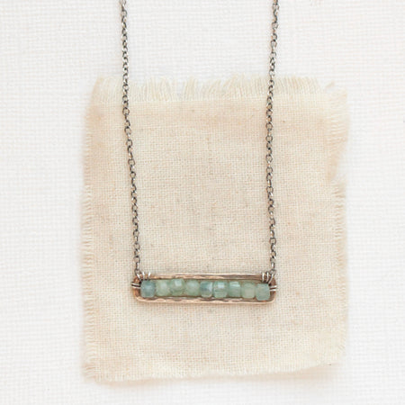 The green apatite beaded bronze bar necklace styled on tan linen
