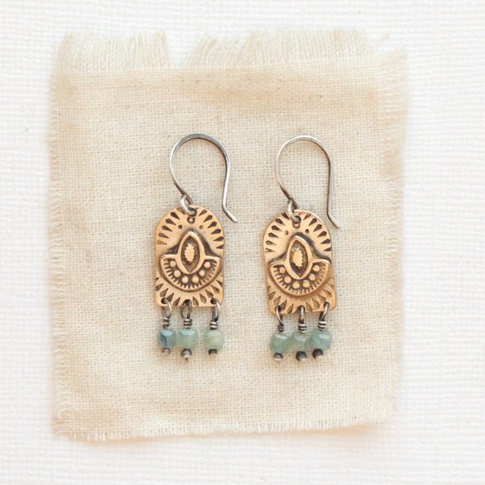 The bronze wanderer arch green apatite earrings styled on tan linen