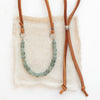 The green apatite adjustable leather necklace styled on tan linen