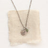 The green kyanite and sprout charm necklace styled on tan linen