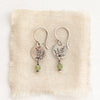 The green kyanite sprout earrings styled on tan linen
