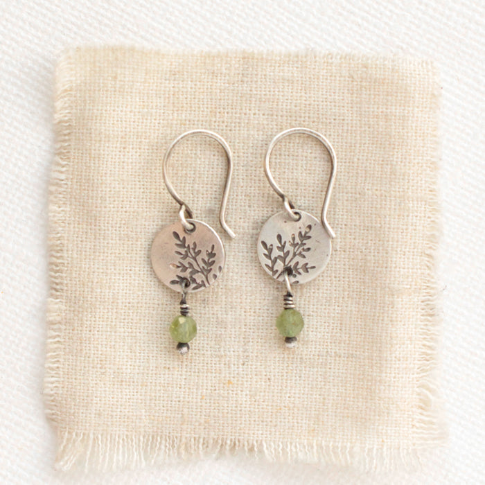 The green kyanite sprout earrings styled on tan linen