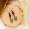 The turquoise heart leather earrings styled on wood with yellow velvet and dried grass