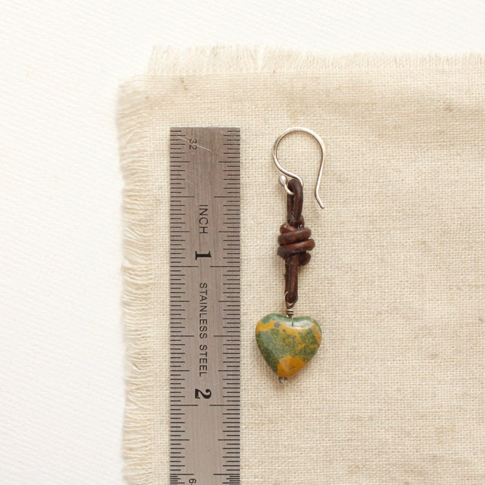 A turquoise leather earring next to a ruler for size reference