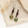 The green turquoise leather earrings styled on tan linen with dried grass