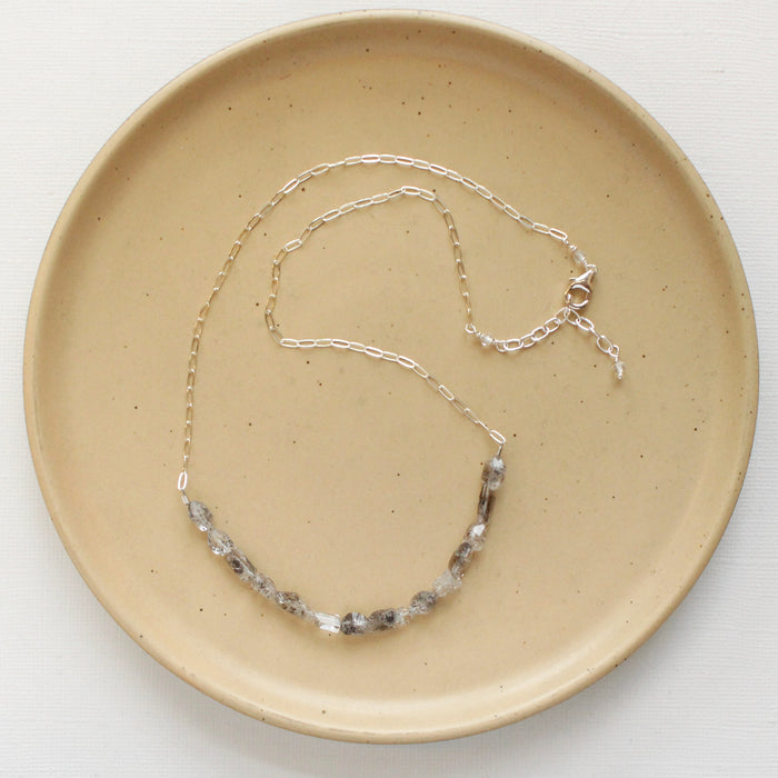 The herkimer diamond collar necklace styled on a tan plate to show the adjustable lobster clasp closure