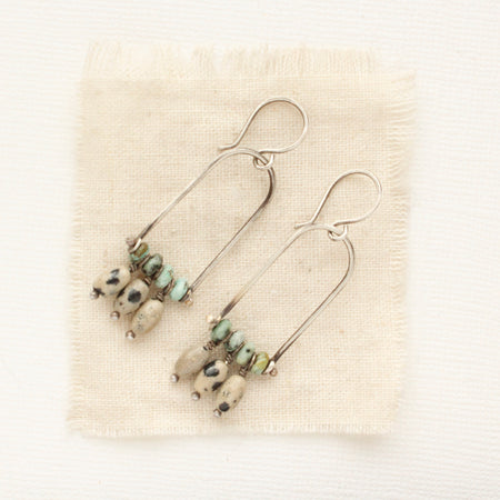 The pinned turquoise and dalmatian jasper silver arch earrings styled on tan linen