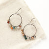 The kaleidoscope hoop earrings styled on tan linen