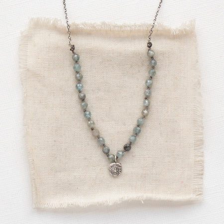 The knotted zircon roma necklace styled on tan linen
