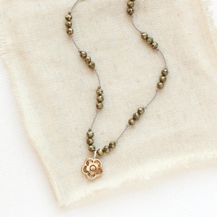 The knotted pyrite and bronze mini cactus flower is styled on tan linen