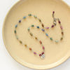 The knotted tourmaline heart necklace styled on a tan plate to show the adjustable lobster clasp closure
