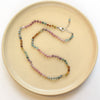 The knotted rainbow tourmaline necklace styled on a tan plate to show the adjustable lobster clasp closure