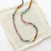 The knotted tourmaline necklace styled on tan linen
