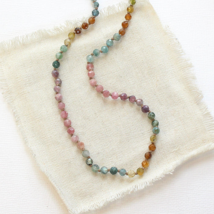 The knotted tourmaline necklace styled on tan linen