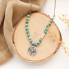 The knotted seaside columbine medallion necklace styled on wood with tan velvet and dried grass