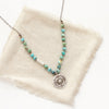 The knotted seaside columbine medallion necklace styled on tan linen