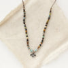 The knotted serenity soar necklace styled on tan linen