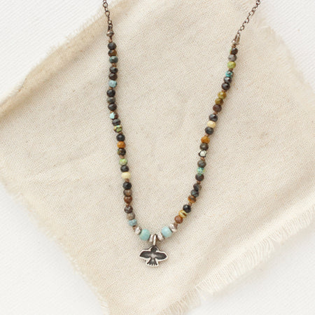 The knotted serenity soar necklace styled on tan linen