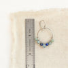 A kyanite and aquamarine hoop earring next to a ruler for size reference