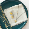 The stacked mythos earrings styled on a blue plate with the matching necklace