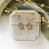 The gold wrapped labradorite post earrings styled on a velvet box with green velvet and dried grass