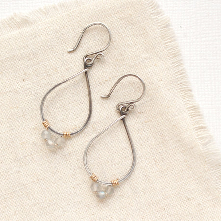 The labradorite wrapped mixed metal teardrop hoop earrings styled on tan linen