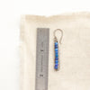 A lapis beaded bar earring next to a ruler for size reference