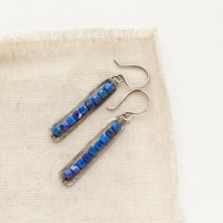 The lapis beaded bar earrings styled on tan linen