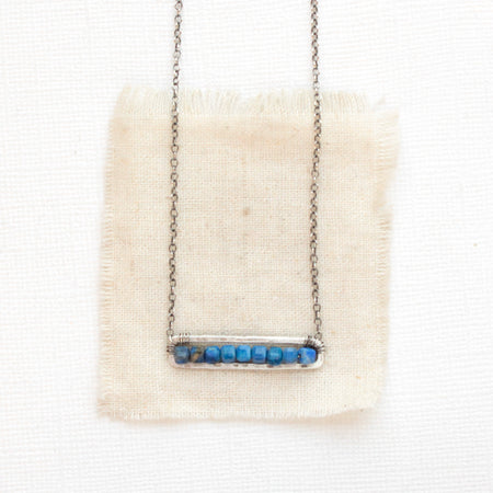The lapis beaded bar necklace styled on tan linen