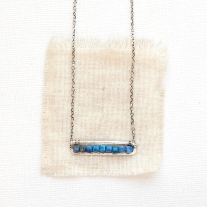 The lapis beaded bar necklace styled on tan linen