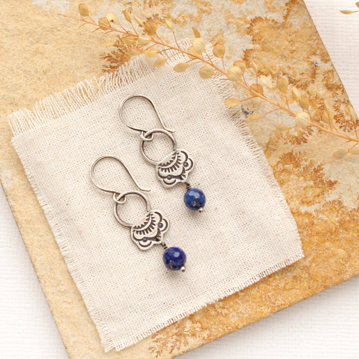 The lapis jolie earrings styled on a tan rock with linen and dried grass